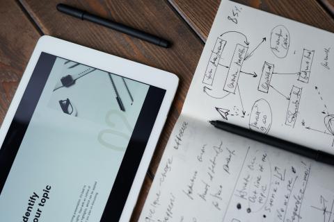 A snapshot of tablet and a notebook placed on a wooden table