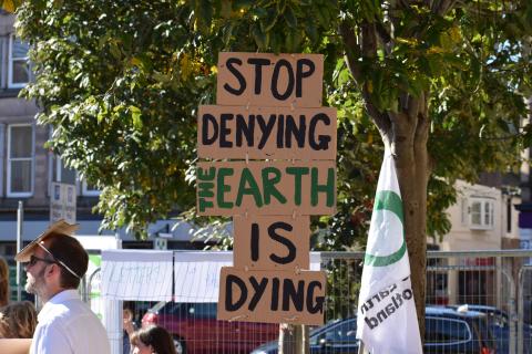 "Stop denying the Earth is dying" written on a cardboard during a protest